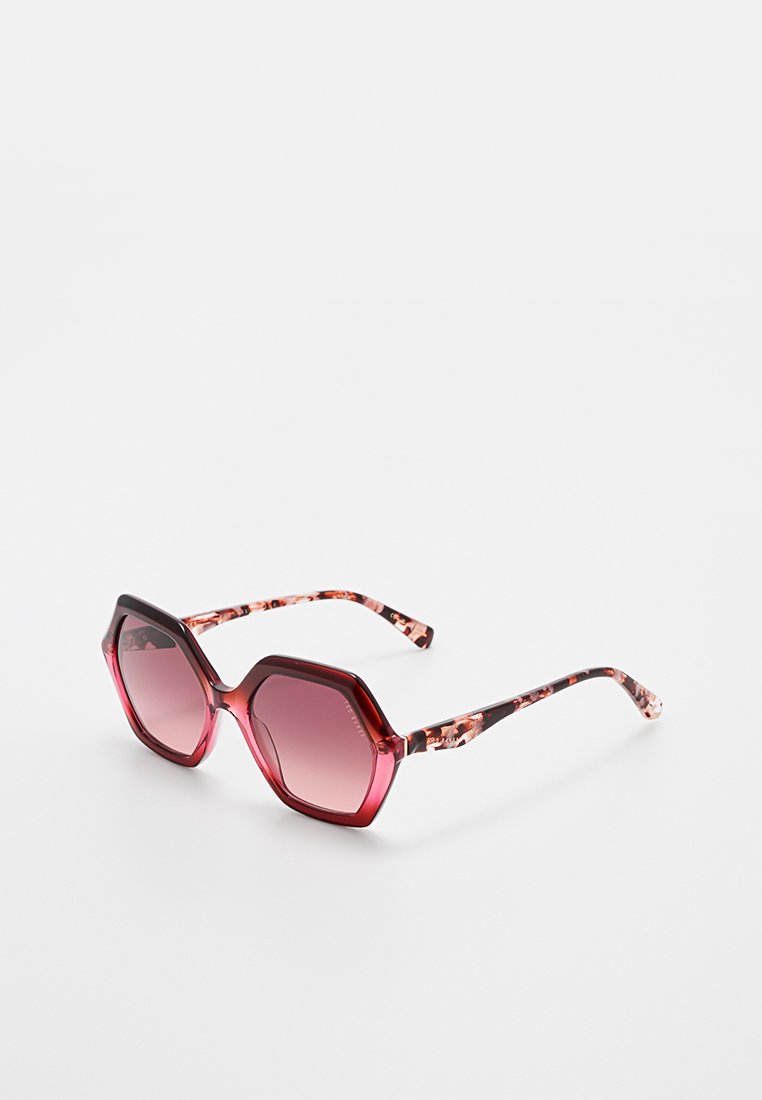 Hexagonal sunglasses with dark red gradient lenses, featuring a patterned tortoiseshell design on the temples and glossy finish.