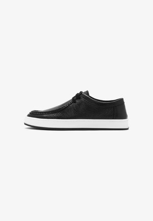 Black leather casual shoe with lace-up front and white rubber sole, viewed from the side on a white background.