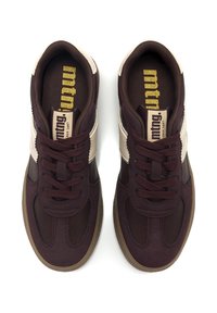 Sneaker bordeaux scuro con superiore testurizzato, punta tonda, accenti crema a contrasto e suola in gomma marrone con lacci.