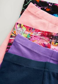 Pile de leggings unis en bleu marine, violet, rose et deux motifs abstraits multicolores, pliés pour montrer les ceintures.