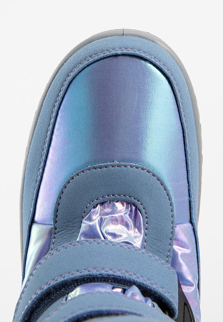 Helles blaues Sneaker mit schillernden Panele, ausgestattet mit Klettverschlüssen, einer Wildleder-Textur und einem gepolsterten Kragen. Gummi-Laufsohle mit grauen Akzenten.