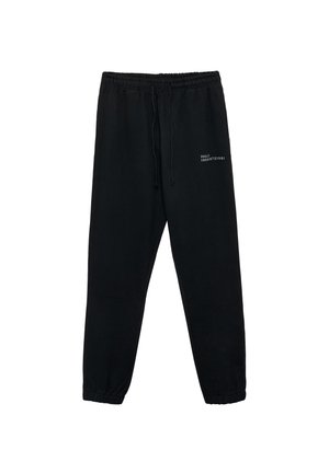 Sorte sweatpants lavet af blødt stof, med elastisk talje og snøre, manchetter ved anklerne og hvid tekstdetalje på forsiden.