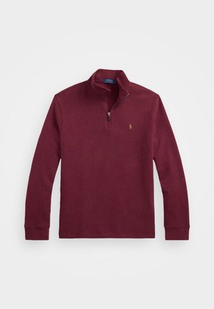 Sweater bordeaux com fecho éclair e mangas longas, apresentando um gola alta, punhos canelados e um pequeno logótipo bordado no peito. Material em mistura de algodão.