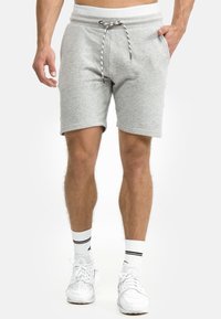 Grå bomuldsshorts med snoreliv, sidelommer og en afslappet pasform. Stilen har en sort og hvid stribet snor.