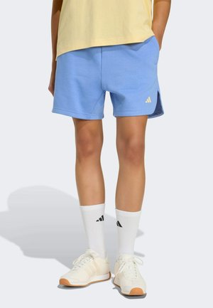Shorts de sport bleu clair avec poches latérales, en matériau doux. Associés à des chaussettes blanches à rayures noires et des baskets crème.