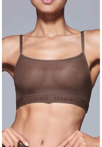 Bruine bralette gemaakt van gladde stof met dunne bandjes en een geborduurde elastische band met "ITEM m6" in bijpassende kleur.