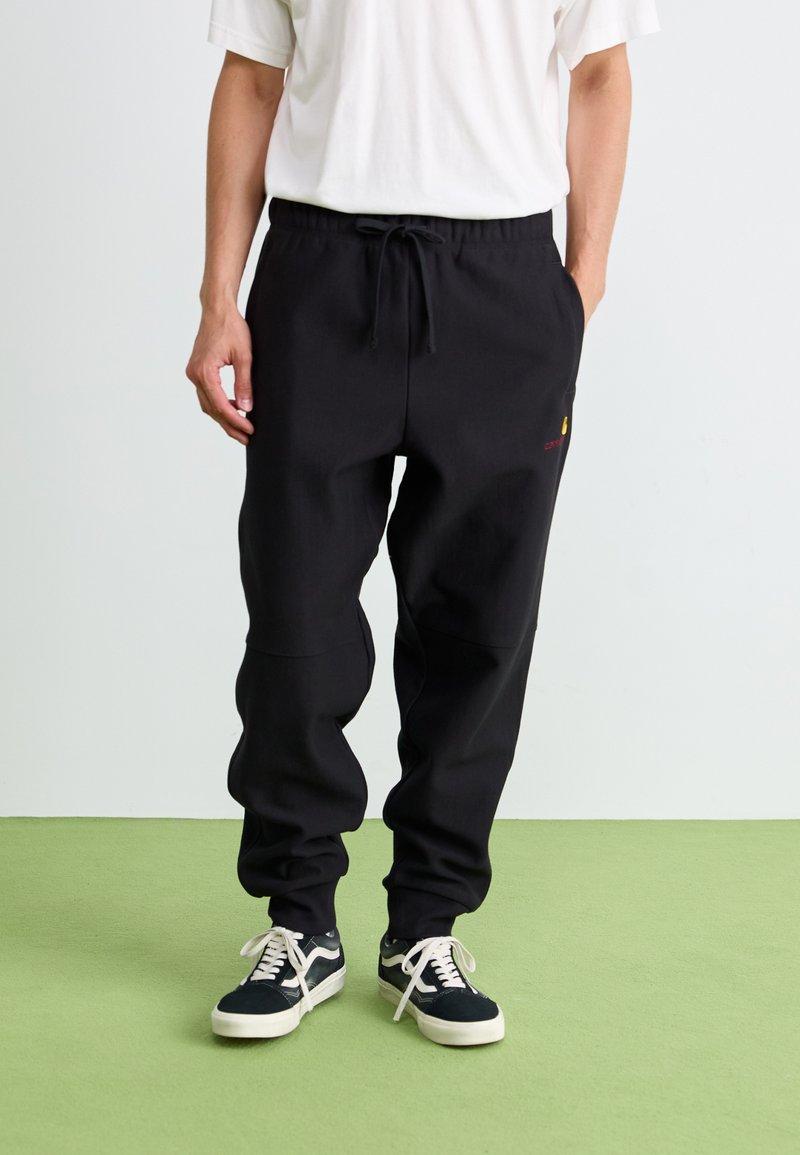 Pantaloni sport negri, cu talie ajustabilă prin șnur, având un detaliu subtil cu logo. Fabricat dintr-un material neted, cu croială conică și manșete elastice.