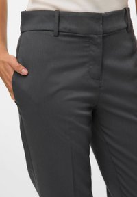 Grå skreddersydde bukser laget av glatt materiale, med rett ben-design og sidelommer. Livet er flatt med beltehemper.