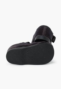 Scarpa in suede nera con punta rotonda, suola in gomma, cinturino regolabile e piccolo dettaglio con fibbia sul tallone. Parte superiore testurizzata e finitura liscia.