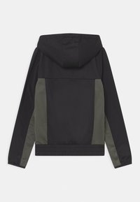 Kapuzenshinterjacke mit schwarzer Front, dunkelgrünen Seitenpanelen und elastischen Bündchen sowie Taillenbund. Strukturierter Stoff mit matter Oberfläche.