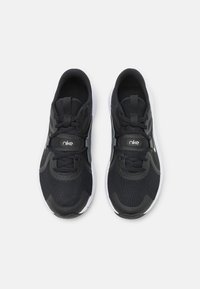 Zwarte sportieve schoenen van mesh en synthetische materialen, met een witte zool, ronde punt en tonale accenten. Veters en logo bovenop.
