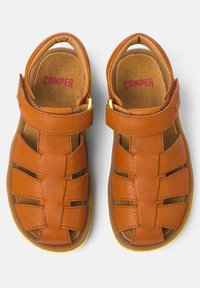 Braune Ledersandalen mit einer strukturierten Oberseite, ausgestattet mit Riemen, Klettverschluss und gelben Akzenten an der Sohle. Größe und Marke sind innen sichtbar.