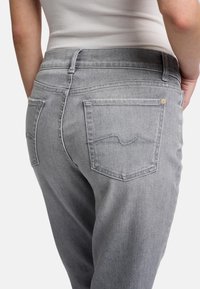 Jeans in denim grigio con un classico design a cinque tasche, dotati di cuciture chiare sulle tasche posteriori e una texture liscia.