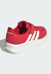 Červená športová obuv s bielymi pruhmi, vybavená polstrovaným golierom a suchým zipsom. Ľahká podrážka cloudfoam pre pohodlie a podporu.