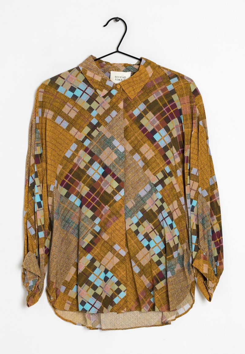 Chemise marron à boutons avec un motif de tartan géométrique comprenant des couleurs telles que le vert, le bleu, le rose et le bordeaux. Tissu légèrement texturé.