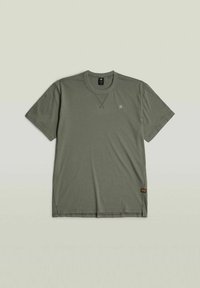 T-shirt à manches courtes vert olive en tissu doux, avec un col rond, des fentes sur les côtés et un petit logo sur la poitrine.