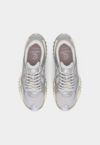 Ζευγάρι γκρι και λευκά αθλητικά παπούτσια Converse με κορδόνια, υφασμάτινο πλέγμα και μπεζ σόλες, σε θέα από πάνω πάνω σε λευκό φόντο.