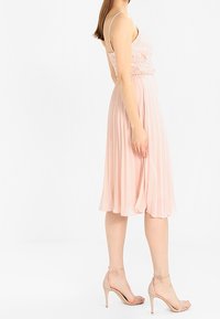 Kleid ihaala vaaleanpunaiseksi laskostetuksi, jossa on pitsiyläosa, ohutolkaimiset ja tiukka yläosa. Yhdistettynä ihonvärisiin korkokenkiin. Yksinkertainen ja tyylikäs muotoilu.