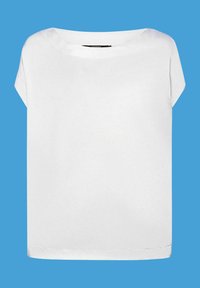 Blouse blanche à manches courtes avec un col rond présentée sur un fond bleu.