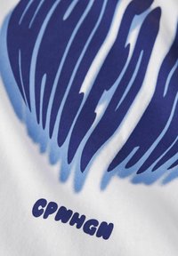 Tissu blanc avec des rayures ondulées bleues et bleu marine. Le texte "CPNHGN" apparaît en lettres grasses et arrondies sous le design. Texture lisse.