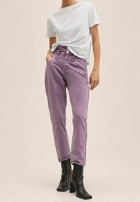 Jeans de mezclilla morados con un corte recto, cintura alta y cinco bolsillos, combinados con una camiseta blanca de manga corta y botas negras de tacón.