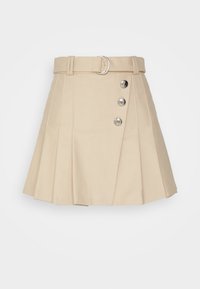 Jupe plissée beige avec une ceinture assortie et trois boutons décoratifs argentés sur le côté droit devant.