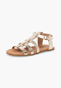 Sandale gladiateur plate dorée métallique pour femme avec plusieurs brides et boucle de cheville ajustable sur semelle couleur cuir, présentée sur fond blanc.