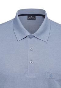 Hellblaues Poloshirt aus strukturiertem Stoff, mit zwei Knöpfen und einer Tasche, die ein kleines blaues Emblem zeigt. Weiches Strickmaterial und atmungsaktives Design.