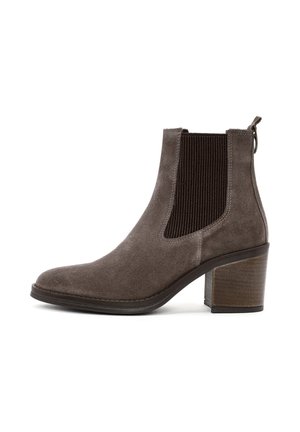 Stivale alla caviglia in suede marrone con pannelli laterali elasticizzati, punta affilata e tacco in legno impilato. Dotato di una linguetta per una facile calzata.