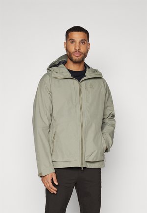 Veste imperméable vert clair avec capuche, présentant un motif à carreaux, des poches zippées et des poignets réglables pour un ajustement sécurisé.