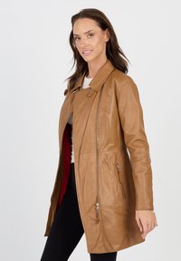 Helle Leder-Trenchcoat mit Kragen, schrägem Reißverschluss und zwei Seitentaschen. Innen mit rotem Stoff gefüttert und in einem eleganten, taillierten Design.