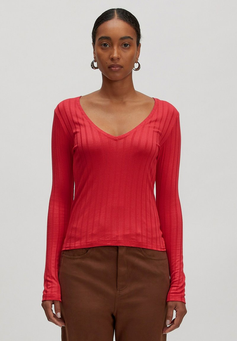 Rotes Langarmshirt mit V-Ausschnitt, aus geripptem Stoff gefertigt. Das Design zeichnet sich durch vertikale Streifen und eine figurnahe Silhouette aus.