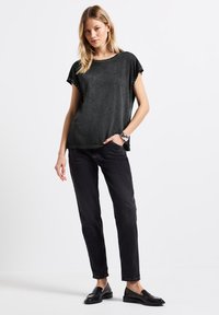 T-shirt noir à manches courtes, à coupe décontractée, avec des accents cloutés sur les manches. Associé à un pantalon noir slim et des mocassins.