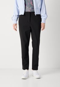 Zwarte tapse broek in lichtgewicht materiaal, met voorplooien, een soepele textuur en zijritsen, gecombineerd met witte sneakers.