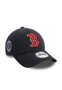 Gorra de béisbol navy con logo bordado en rojo "B" y parche lateral. Cuenta con una visera curvada y ojales ventilados. Ajuste regulable.