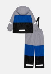 Tweedelige regenpak voor kinderen in grijs, blauw en zwart. Heeft een capuchon, reflecterende accenten en een elastische tailleband op de broek. Soepele textuur.