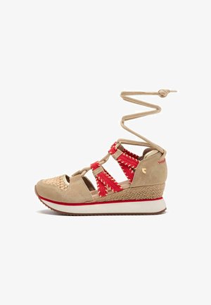 Sandalía de cuña de ante beige con acentos rojos tejidos, puntera redonda, correas para el tobillo y una suela de cuña texturizada. Presenta una entresuela blanca y una suela de goma.