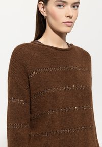Brauner Strickpullover mit horizontalen Streifen aus kleinen metallischen Akzenten. Verfügt über einen weiten Ausschnitt und einen weichen, strukturierten Stoff.