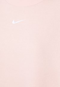Ljusrosa sweatshirt tillverkad av mjukt bomullsblandat tyg. Har en ribbad halsringning och vit Nike-logotyp på bröstet. Enkel, minimalistisk design.