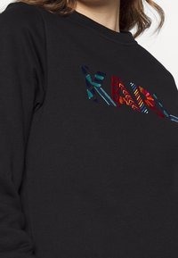 Černá mikina s multicolor vyšívaným textem a geometrickými vzory. Vyrobena z měkkého materiálu s klasickým designem kulatého výstřihu.