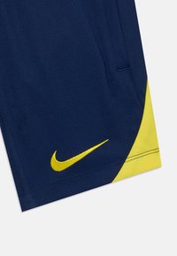 Mornarsko plave atletske kratke hlače s žutim Nike logotipom, koje imaju žuti naglasak na rubu. Izrađene su od lagane, prozračne tkanine.
