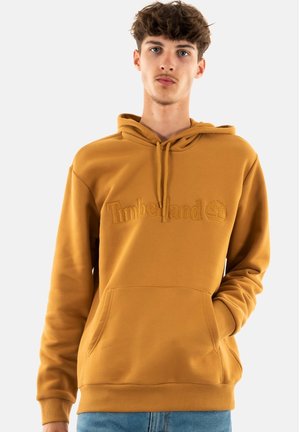 Hoodie w kolorze musztardowym z przednią kieszenią i kapturem ze sznurkiem. Posiada wytłoczone logo "Timberland". Gładka tkanina i luźny krój.