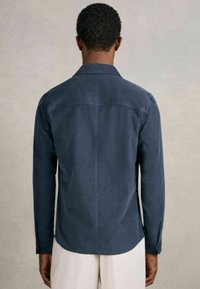 Navyblaue Langarmbluse aus glattem Stoff mit Stehkragen, Rückennaht und knöpfbaren Manschetten, im lässigen Schnitt.