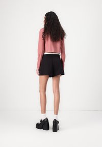 Red and white checked cropped shirt, black shorts, black platform shoes, white socks. Smooth fabric, short sleeves, and high-waisted design.