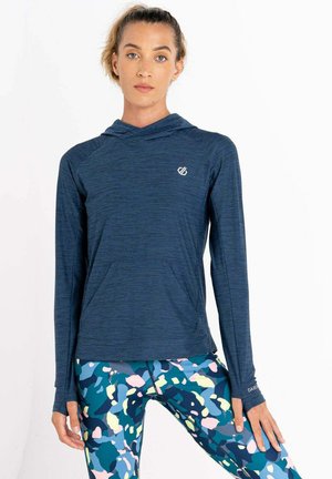 Marineblaue Langarm-Hoodie mit einer Vordertasche und strukturiertem Stoff. Kombiniert mit eng anliegenden, mehrfarbigen Leggings im abstrakten Muster.