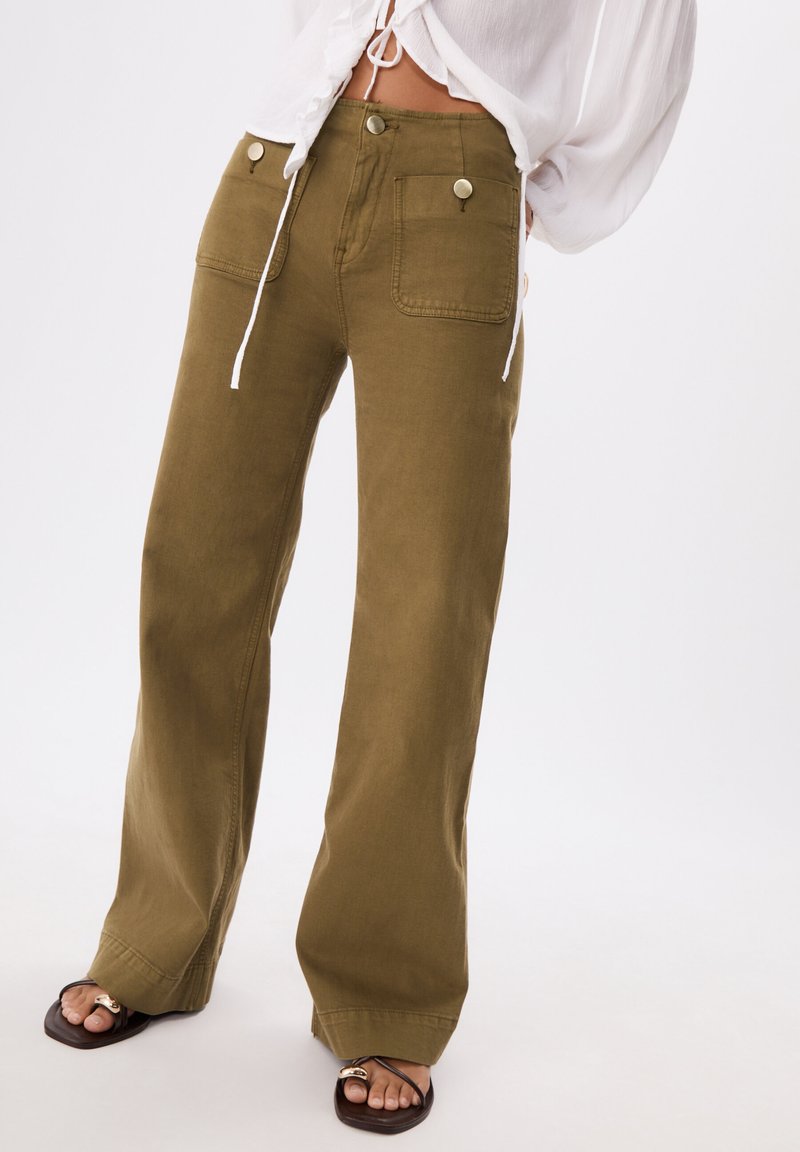 Olivgrüne weit geschnittene Hose aus robustem Stoff, mit zwei vorderen Taschen mit Knopfakzenten und hohem Bund.