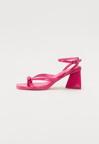 Rosa patentlær heeled sandaler med firkantet tå, smale stropper og en geometrisk blokklitt. Har en spenne detalj på stroppen.