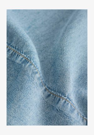 Heledat sinine denim kanga sile tekstuur, mille servadel on nähtavad õmblused ja väiksed värvi variatsioonid.