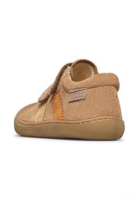 Scarpa in suede marrone con cinturino in velcro, dotata di una suola in gomma texture e pannelli a contrasto arancioni e beige. Forma arrotondata, texture morbida.