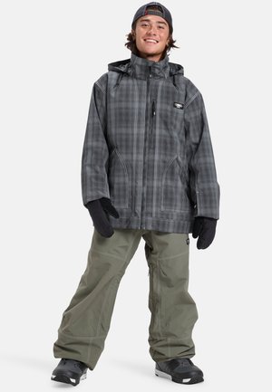 Veste de neige à carreaux gris avec une capuche, fermeture éclair à l'avant et poches pour les mains. Associée à un pantalon de neige vert olive et des bottes d'hiver noires. Gants noirs inclus.